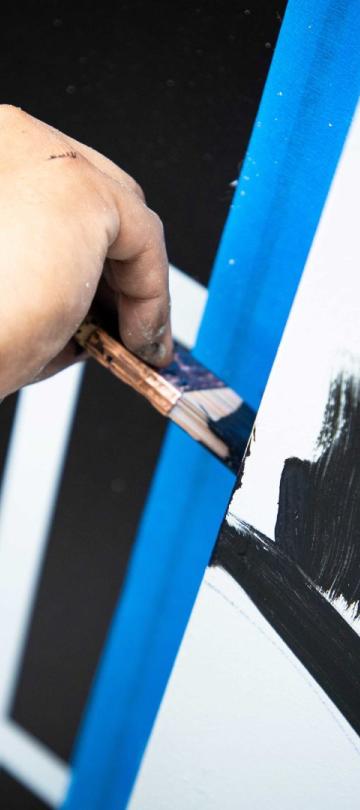 A No Kings Collective artist paints graffiti on the exterior of Viceroy Washington DC