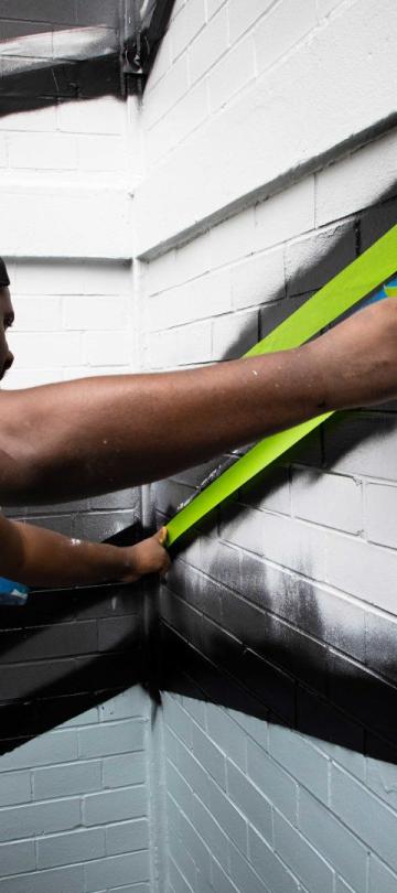 A No Kings Collective artist paints graffiti on the exterior of Viceroy Washington DC
