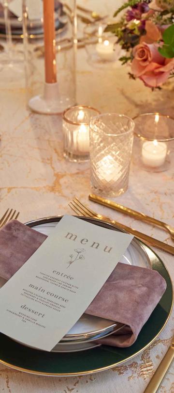 An elegant place setting with gold cutlery and floral centerpieces on a white tablecloth at Viceroy Washington DC