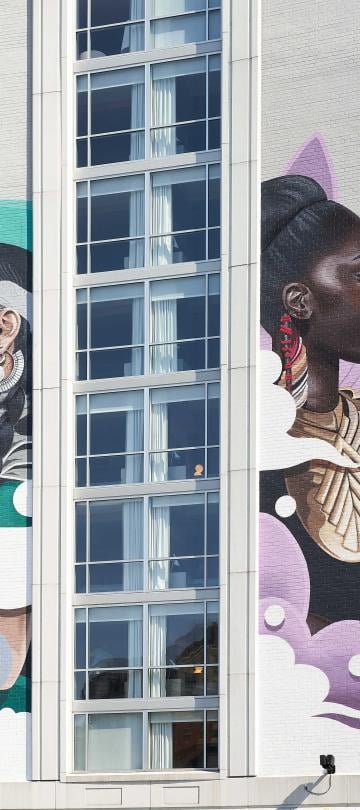 A mural of two women surrounded by neon colors, spanning five stories in height