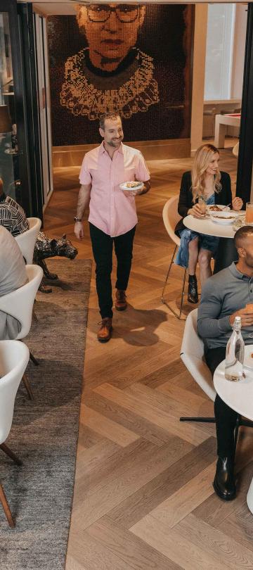 An aerial view of the dining room full of patrons at Hotel Zena's Figleaf restaurant, with a row of booths and two-top white tables