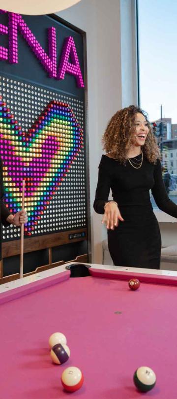 Two women shoot pool on a pink pool table at Hotel Zena's Figleaf restaurant