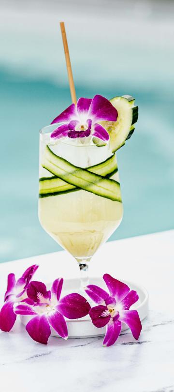 A cucumber cocktail decorated with purple flowers