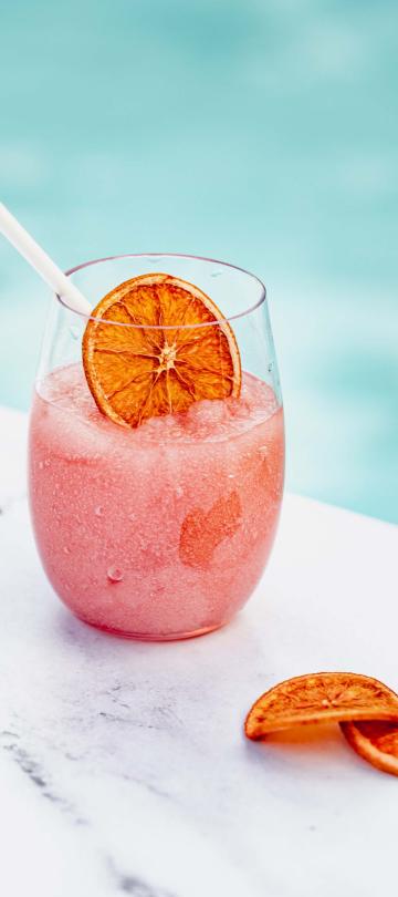 A pink fizzy cocktail garnished with oranges