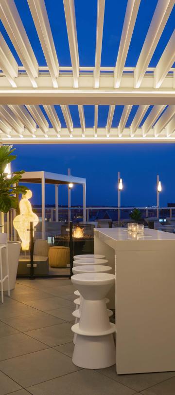 Hedy's Rooftop, a chic patio with heat lamps and a white lattice canopy, at night