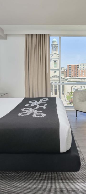 A king bed, dresser, TV, chair, and balcony in a room at Viceroy Zena Washington DC