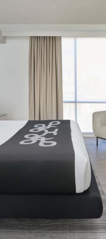 A king bed, dresser, and corner chair in a room at Viceroy Zena Washington