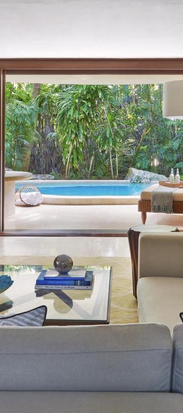 The living space with couches and chairs and a patio with a private pool at Viceroy Riviera Maya