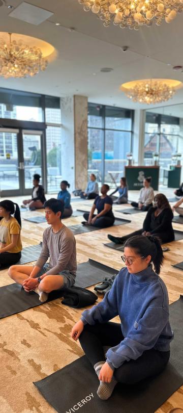 group class of people sitting cross-legged on black yoga mats
