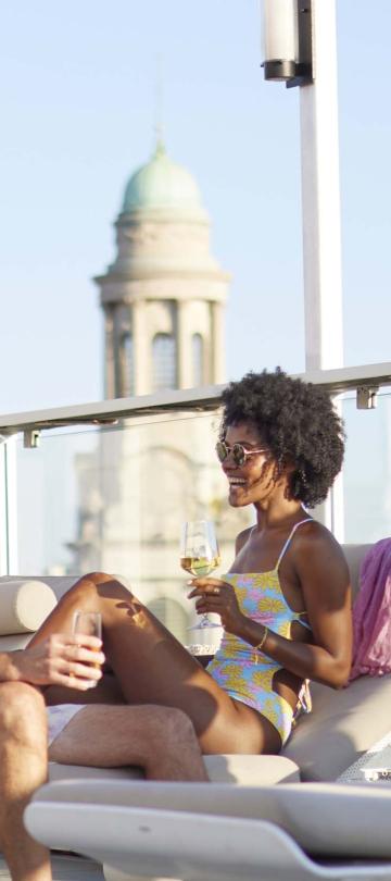 two people sit on rooftop chairs near pool