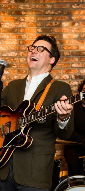 Nick Waterhouse smiling while playing guitar at Viceroy with his band