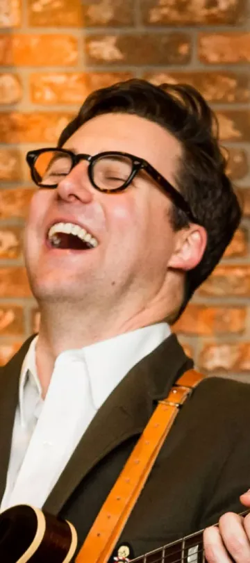 Nick Waterhouse smiling while playing guitar at Viceroy with his band