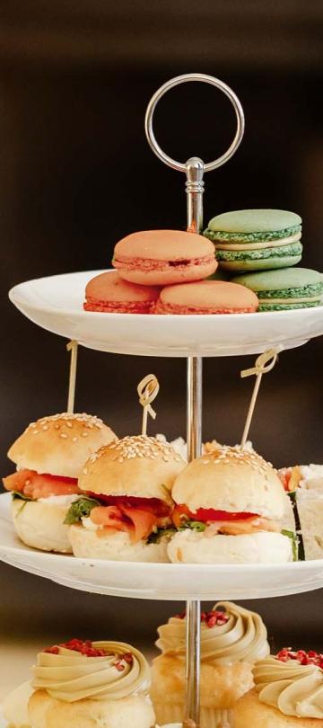 A tea tower of sandwiches and macarons, with two glasses of champagne