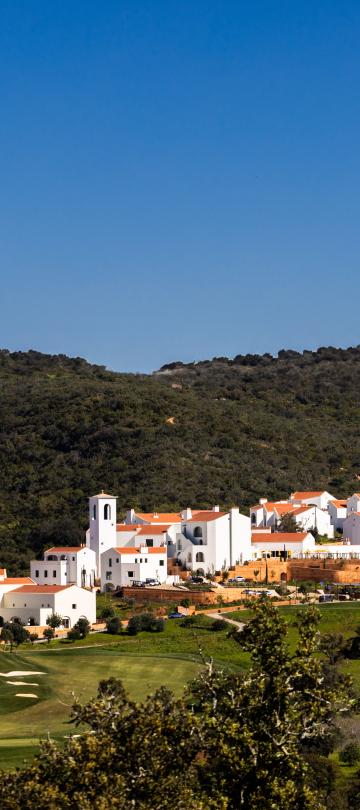 Viceroy Ombria Algarve, a gleaming white resort in the valley of a large, lush green hill