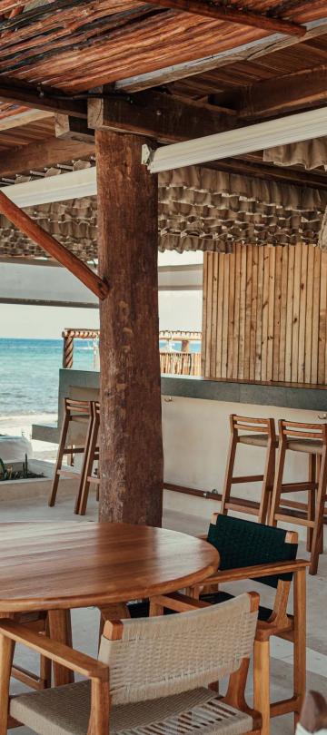 Coral Grill + Bar at Viceroy Riviera Maya, with two patrons having a drink at the bar in view of the ocean