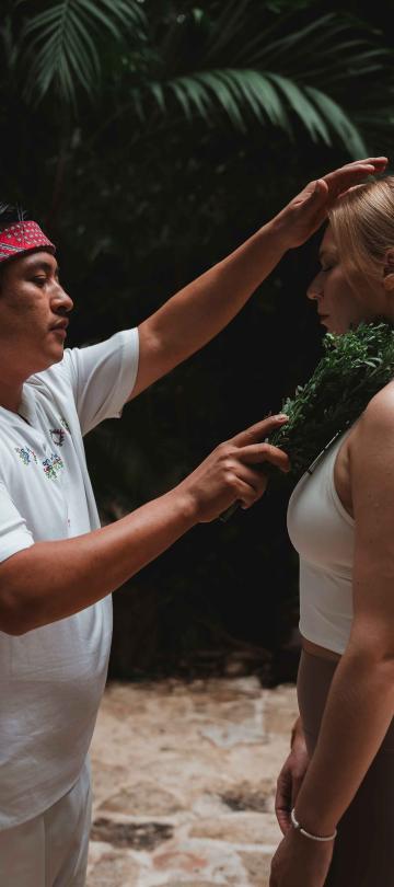 A man with sage healing a woman at Riviera Maya