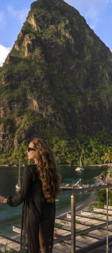A woman standing on a balcony looking at the ocean at Spice of Life Residence