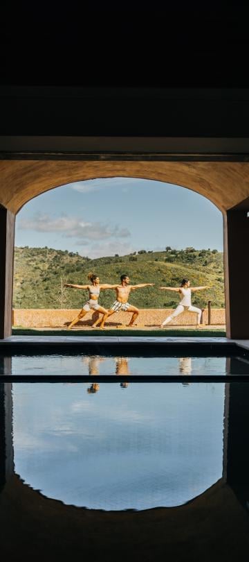 group of people doing yoga pose in background with water in foreground