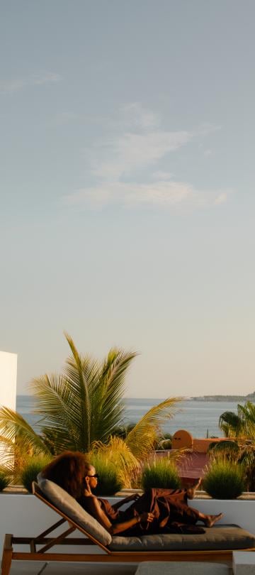 A woman sits beside the pool reading.