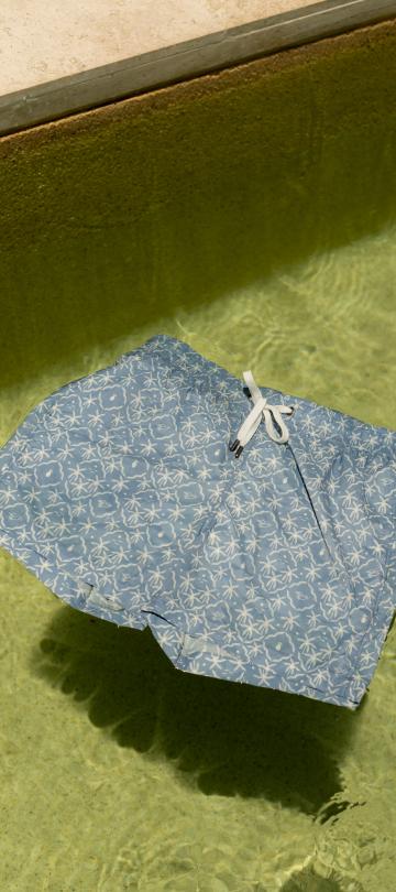 A pair of Onia x Viceroy swim trunks float on crystal clear water.