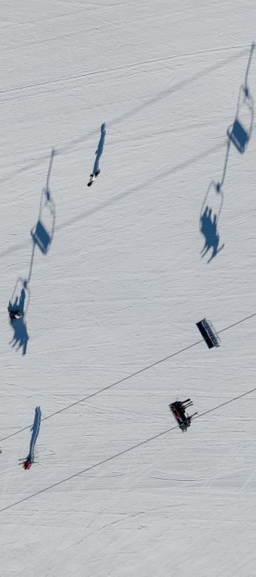 An aerial view of the ski lifts, with the shadows of the lift sharply contrasting the snow below