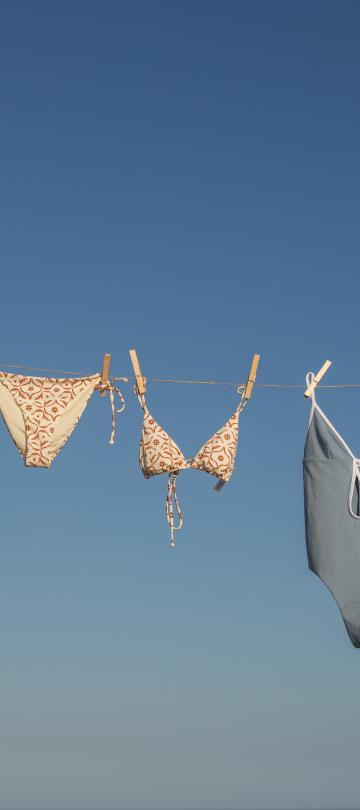 Bathing suits hang on a clothesline.