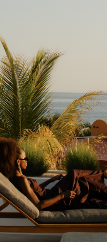 a woman relaxing on a lounge chair on a ocean-view terrace at a Viceroy Resort