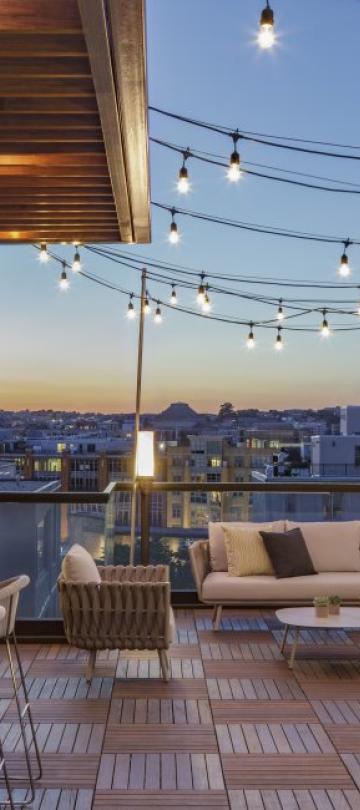 Hush, the rooftop patio bar at Viceroy Washington DC, at dusk. String lights illuminate the wood-panelled decor