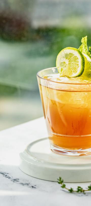 A refreshing cocktail garnished with lime and mint, on a marble table at Hedy's rooftop