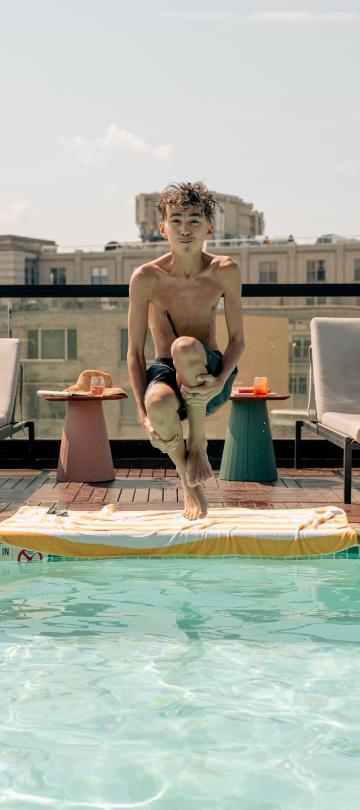 A boy does a cannonball jump into the pool at Hush, the rooftop patio bar at Viceroy Washington DC