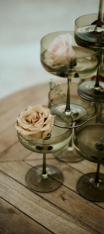 A beautiful arrangement of wine glasses with roses in them