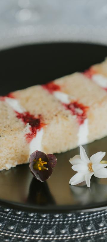 A beautiful cake piece on a black plate 