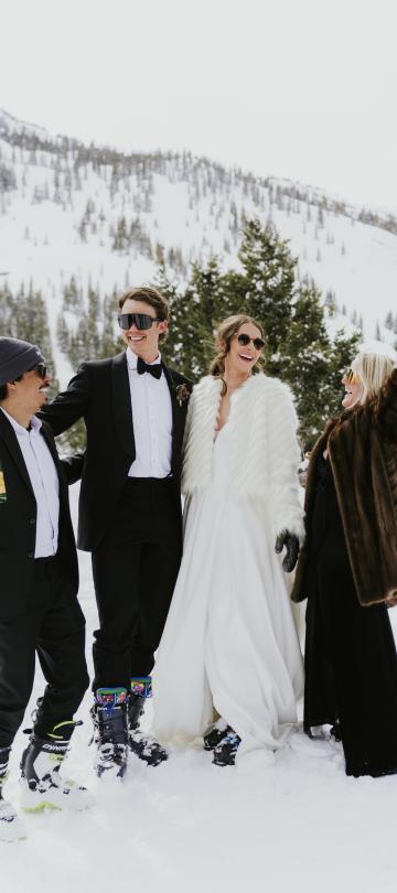 The bride and groom and their friends celebrating in the snow with champagne 
