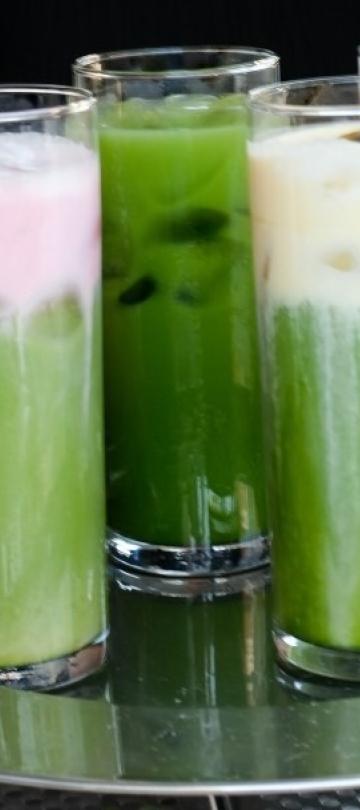 A person holding a tray of matcha drinks