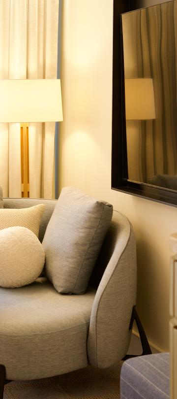 Curved grey sofa with throw pillows and table set with champagne beside a modern TV setup.