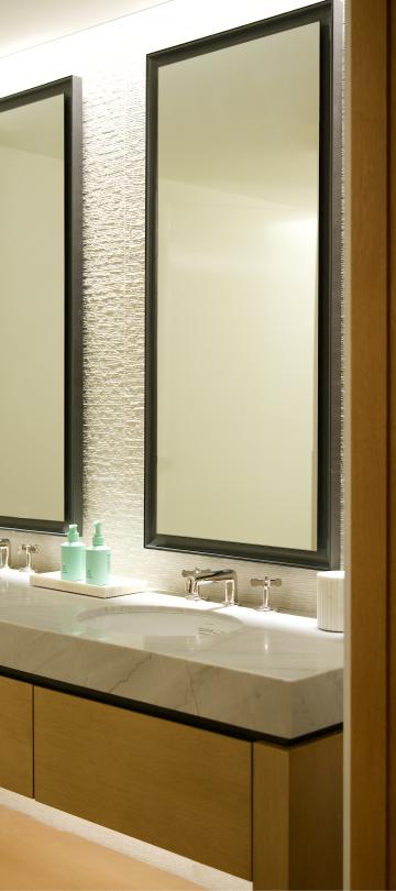 View through an open doorway of a hotel bathroom double vanity with two black-framed mirrors.