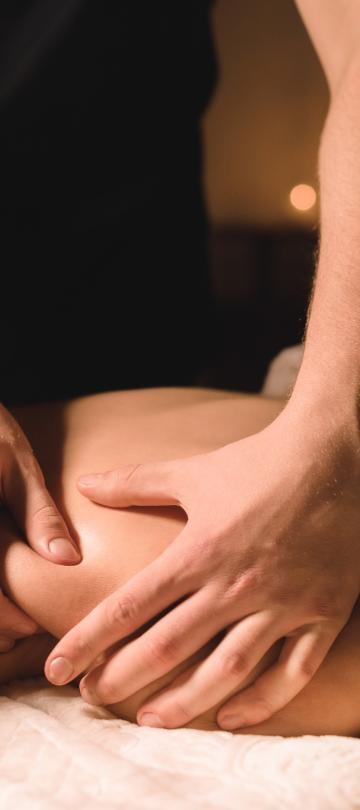Uma mulher deitada de costas a receber uma massagem nas costas no spa