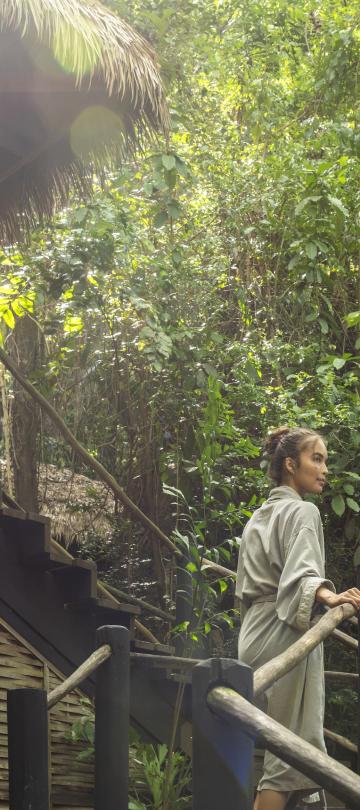 A woman ascends an outdoor staircase in a bathrobe
