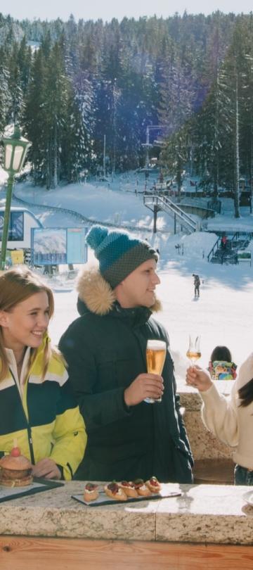 A group of skiers relaxing on a patio overlooking the mountain