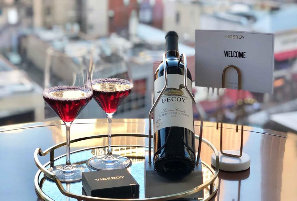 two glasses of red wine and a bottle sit beside a placecard