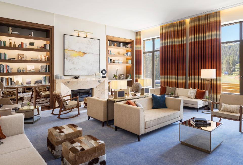 The Library, an airy lounge at Viceroy Kopaonik Serbia, with ample comfortable seating and several wall-to-ceiling bookshelves and a view of the mountain
