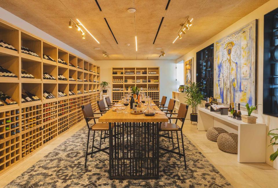 Viceroy Los Cabos' Wine Room, a bright cellar with floor-to-ceiling wine racks, surrounding a large dining table