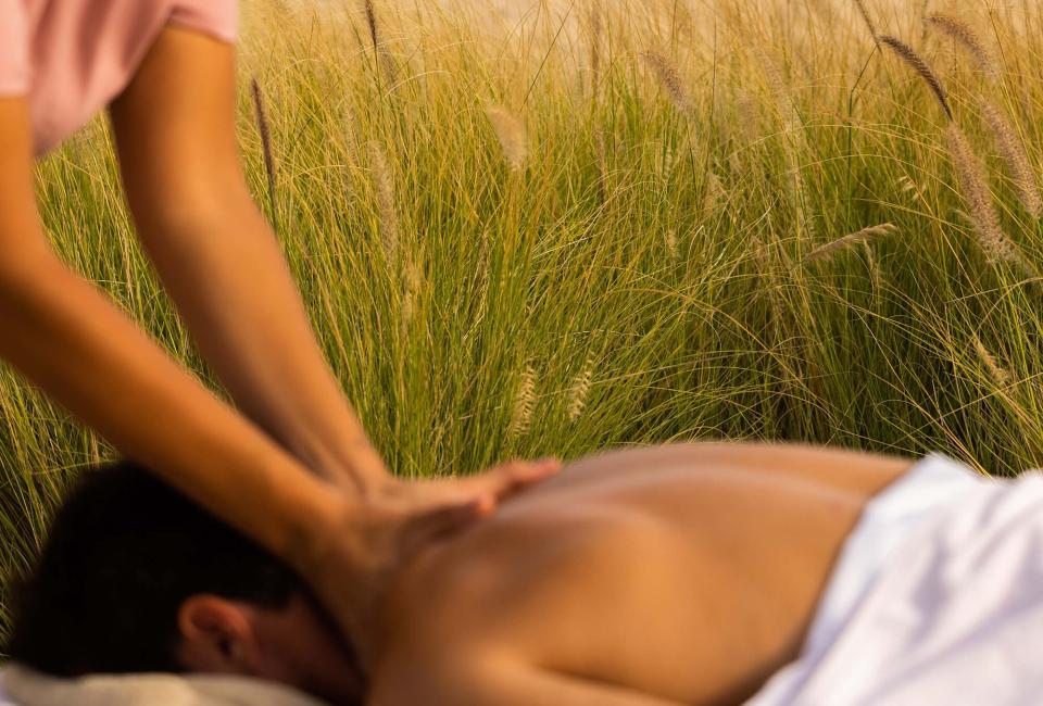 A man receives a massage outdoors next to the beach in Los Cabos
