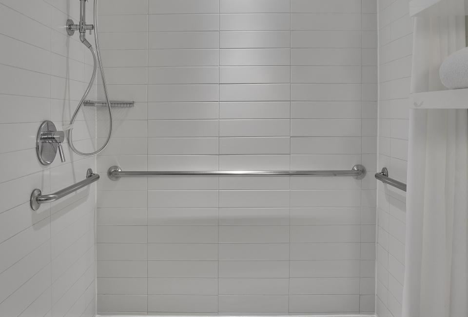 An accessible shower, with a large square footage and a waist-height grab bar, in a Viceroy Washington DC hotel room