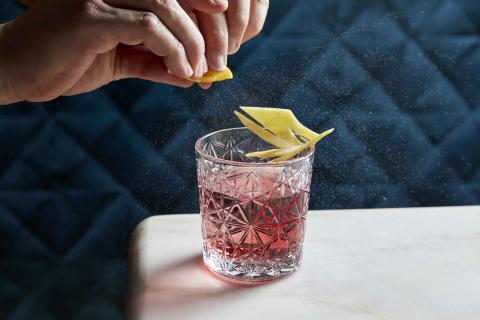 A person squeezing lemon in their cocktail