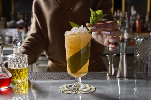 Bartender adding mint garnish to a cocktail