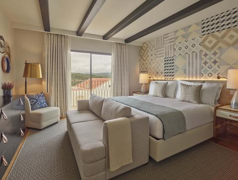 Bedroom with sofa at the foot of the bed and a small chair
