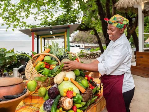 A woman staking fruit and vegetables at a stand