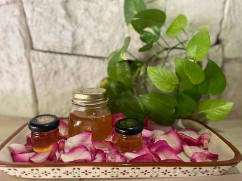 Jars of honey on a tray of flower petals