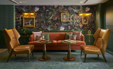 Green room with gold and orange accents including two chairs and a couch